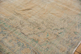 Distressed vintage Oushak carpet with worn beige and gold pile, hints of pale green, fringed edge.