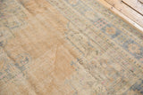 Distressed Oushak carpet showing worn pile, visible foundation, with faded beige and blue patterns.