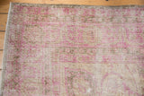 Distressed Sivas carpet pile showing worn pink and beige floral motifs with visible foundation.