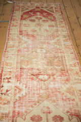 Distressed vintage Oushak runner close-up, displaying worn pale raspberry red and antique ivory tones.