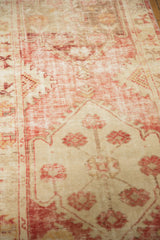 Decorative wear on a vintage distressed Oushak rug, with raspberry red and ivory motifs.