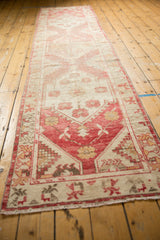 Distressed vintage Oushak runner end, showing fringe, faded raspberry red, antique ivory patterns.