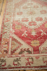 Distressed Oushak runner detail: dusty raspberry red, blush, and ivory motifs with mostly even wear.