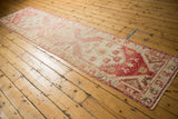 Distressed Oushak runner corner showing pale raspberry, blush, ivory, beige texture with visible knot heads.