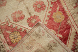 Distressed Oushak rug corner, worn pale raspberry and ivory floral pile, with woven reverse.