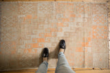 Distressed Oushak rug, ivory and tangerine geometric lattice with worn texture underfoot.