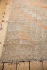 Distressed Oushak rug end with short fringe and faded tangerine orange pattern.