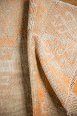 Folded distressed Oushak rug, revealing tangerine and ivory pile alongside the woven foundation.