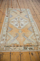 Distressed vintage Oushak runner with pale gold field and geometric border detail.