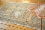 Distressed Oushak rug texture with visible foundation, faded dusty orange, silver, and ivory.