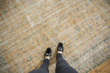 Distressed Oushak rug, pale gold and faded blue texture, shown with black loafers.