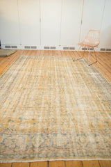 Distressed Turkish Oushak carpet section showing faded gold, blue vinery and textured wear.