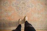 Distressed Oushak carpet showing worn texture in dusty apricot, pale blue, and ivory.