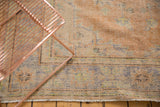 Distressed Oushak rug texture with faded apricot, pale blue, ivory floral motifs, and fringe.