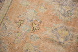 Distressed vintage Oushak rug detail: worn apricot pile and pale blue floral motifs.
