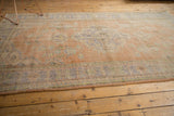 Textured distressed pile with faded apricot and blue floral patterns of the Oushak rug.