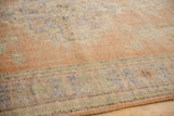 Low, textured pile of a vintage distressed Oushak carpet with border in apricot and pale blue.