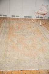 Distressed Oushak pile texture with wear to foundation, featuring apricot, blue, and ivory hues.