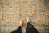 Distressed Oushak carpet, textured with faded floral cross-sections in beige and mint.