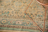 Close-up of distressed Oushak rug: splayed floral vinery, mint green, and intricate border.