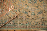 Close-up of distressed Oushak carpet with low pile, beige field, and mint floral border.