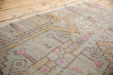 Distressed vintage Oushak rug runner close-up, showing worn pile with pink and saffron geometric motifs.
