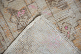Hand-knotted construction, distressed pile texture, and secured ivory selvage of the Oushak runner.
