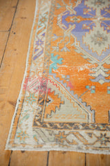 Textured pile of vintage Oushak runner showing distressed tangerine and lavender geometric design.
