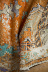 Folded vintage Oushak runner pile displaying distressed tangerine, ivory, and silver tones.