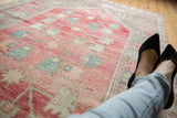 Distressed vintage Oushak runner with faded pink field, sky blue motifs, and soft wear.