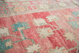 Vintage Oushak runner's distressed pile texture in soft pink, sky blue, and beige.