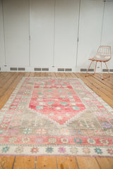 Distressed Oushak runner's geometric border in sky blue, pink, beige, and short ivory fringe.