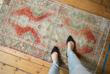 Distressed vintage Oushak rug texture with faded rust red and seafoam green patterns.