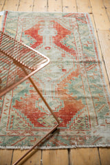 Worn texture and faded rust red, seafoam green, and ivory hues on a vintage Oushak rug.