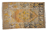 Distressed Oushak rug, saffron yellow stepped medallion on abrash field with charcoal stylized borders.