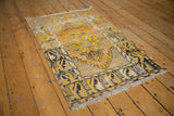 Corner of vintage distressed Oushak rug featuring saffron yellow, charcoal, and serpent motifs.