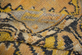 Varied pile texture of a distressed Oushak rug, showing heavy abrash in golden yellow and charcoal.