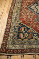 Antique Malayer rug's nuanced rust field, germinating shrubs, and geometric navy blue border.