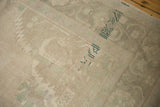Distressed low pile of a vintage Oushak rug in soft beige and muted sea foam green.