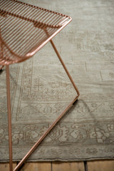 Distressed Oushak rug detail with low pile and faded curvilinear motifs in neutral tones.
