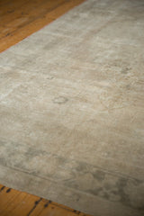 Distressed vintage carpet's low pile, showing faded silver, platinum, and coffee brown motifs.