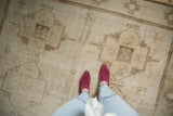 Distressed vintage Oushak rug section with stylized coffee brown birds on an abrashed ivory field.
