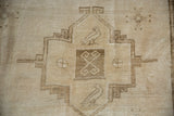 Distressed Oushak rug: Close-up showing stylized bird motif and brown geometric patterns.