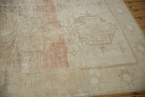 Distressed Oushak rug's low pile texture with faded ivory, sand, and blush.