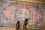 A personal perspective of a distressed Oushak rug highlighting its soft texture and faded colors.