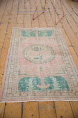 Distressed vintage Oushak runner with faded pink pile and green motifs.