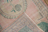 Distressed Oushak rug corner showing worn pink pile and detailed woven foundation.