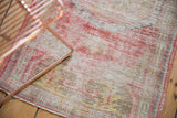 Distressed Oushak rug texture with even wear, exposed foundation, and soft red tones.