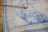 Distressed vintage Oushak rug corner with cobalt blue geometric border and low pile wear.