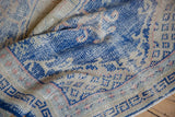 Distressed vintage Oushak rug with cobalt blue and neutral tones, revealing worn pile and foundation.